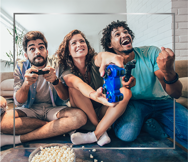 Skupina mladých usmívajících se lidí sedí na podlaze a hraje videohry, jsou šťastní po léčbě plísňové kožní infekce přípravkem Canespor 1x denně roztok